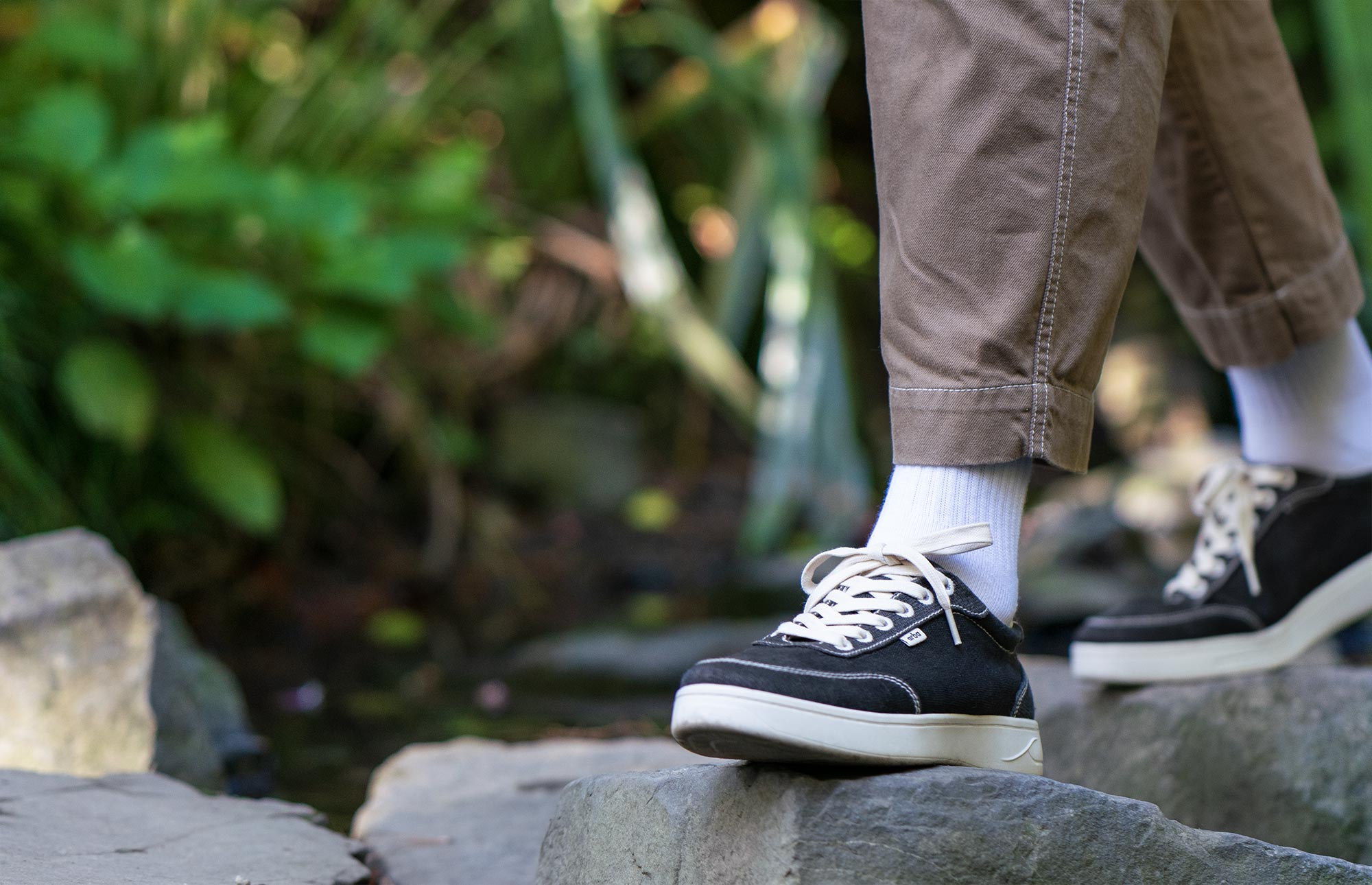 man wearing Orba Black Ghost sneaker on rocks